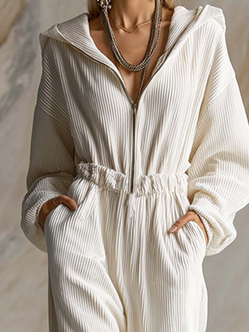 White corduroy hooded jumpsuit by FJØRNA with zip-front closure and long sleeves, displayed on a hanger.