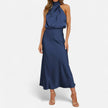FJØRNA draped sleeveless halter maxi dress with flowing fabric and elegant design on a model.