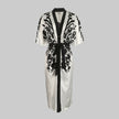 White FJØRNA midi dress with half sleeves, floral print, V-neck, and tied waist for a stylish, feminine look.