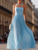 Sky blue FJØRNA halter pleated maxi dress displayed on a hanger with flowing fabric and elegant design.