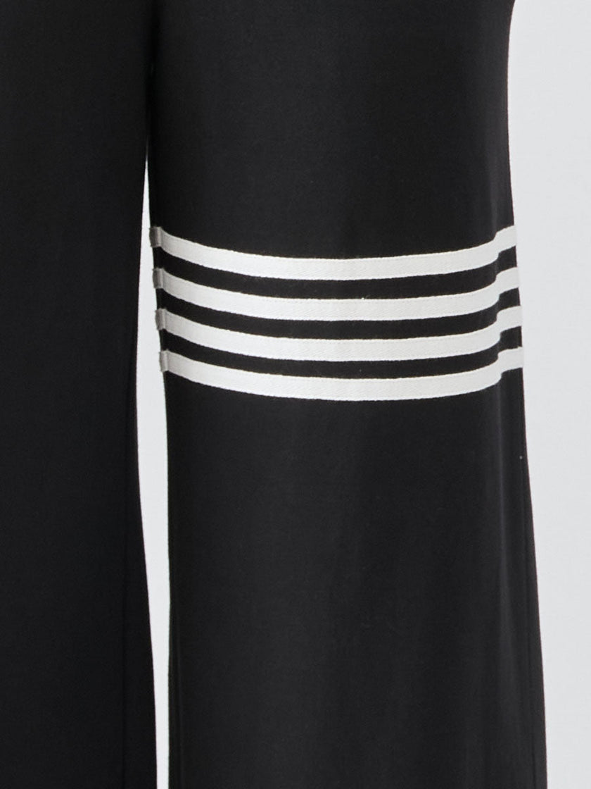 Black striped sleeveless hooded jumpsuit by FJØRNA, featuring a relaxed fit and stylish design, shown on a model.