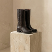 Tan leather men's knee-high boots with block heels and sleek design, featuring laces and sturdy soles by FJØRNA.