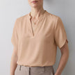 Apricot V-neck short sleeve flowy summer blouse for women by FJØRNA, featuring a relaxed fit and lightweight fabric.