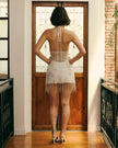 White Amina mini dress by FJØRNA displayed on a hanger, showcasing its lightweight fabric and stylish design.