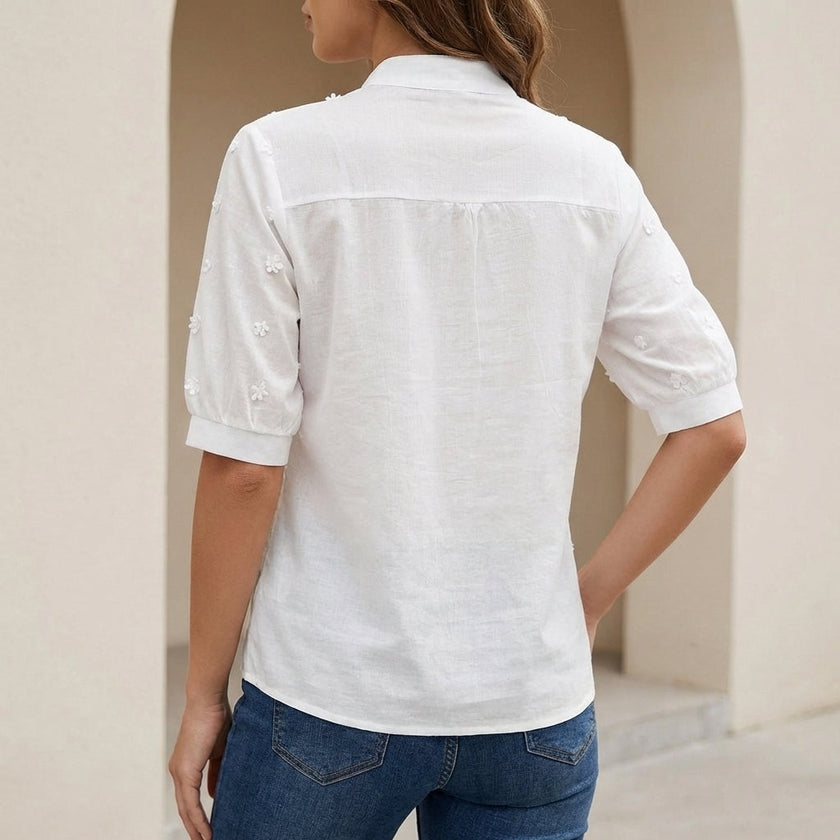 Back view of FJØRNA elegant relaxed fit women's V-neck blouse with embroidered floral details.