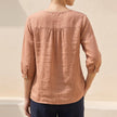 Back view of FJØRNA women's floral cotton summer blouse with lightweight, feminine design and delicate floral pattern.
