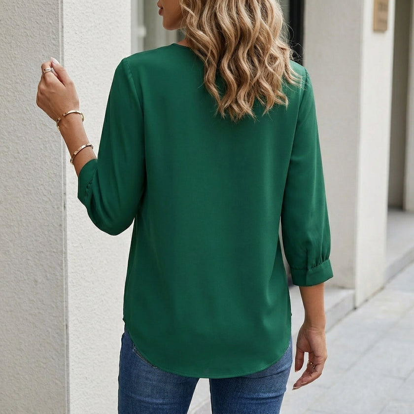 FJØRNA women's summer blouse with V-neck, puff sleeves, and high waist, shown from the back. Light, flowy fabric in natural setting.