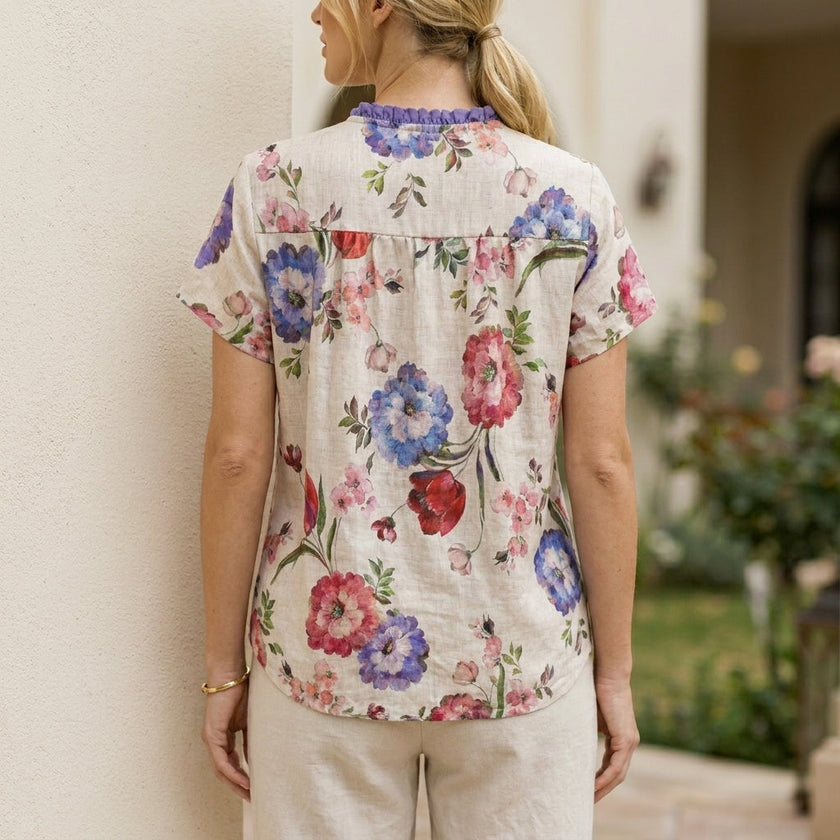 FJØRNA women's floral summer blouse with short sleeves, back view showcasing lightweight fabric and vibrant floral pattern.