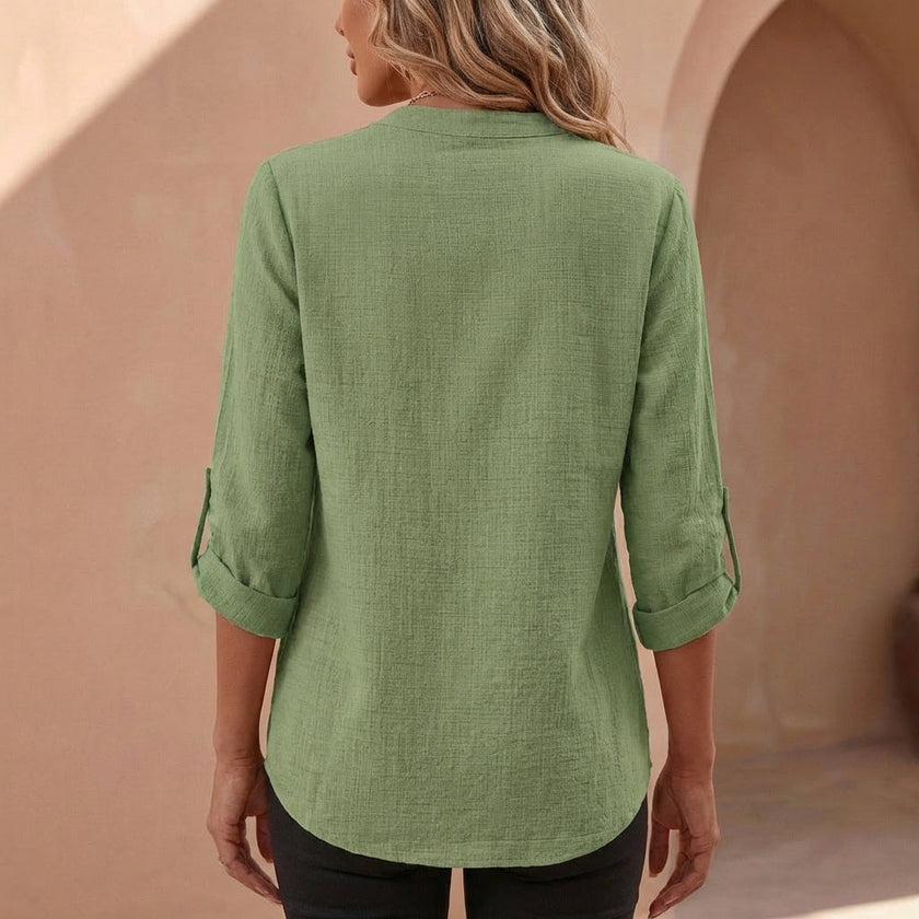 FJØRNA women's relaxed v-neck blouse with band collar and patch pocket, shown from the back with soft fabric and casual style.