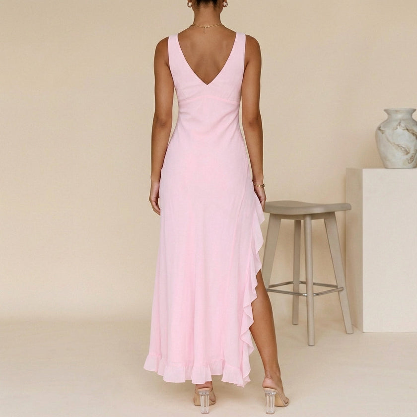 FJØRNA flowing chiffon maxi dress with ruched bodice and ruffled slit, shown from the back with draped fabric and elegant design.