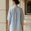FJØRNA women's summer linen blouse with ruffle details, shown from the back, lightweight and breathable top for warm weather.