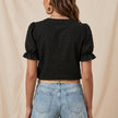FJØRNA summer women's blouse with floral print, puff sleeves, and ruffle details, shown from the back.