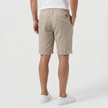 Back profile of men's khaki linen shorts by FJØRNA with elasticated waist and drawstring, perfect for summer beachwear.