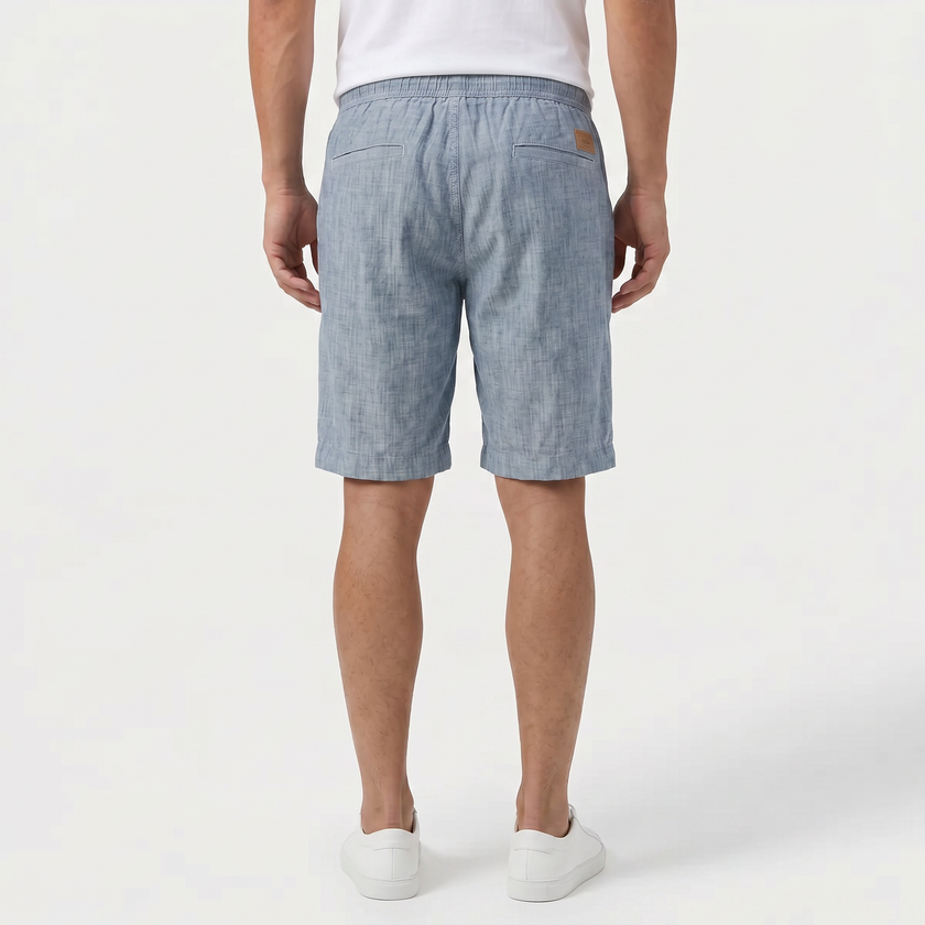 Back view of men's light blue linen shorts with elastic waistband and drawstring, designed for summer beachwear by FJØRNA.