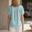 Back view of FJØRNA women's summer blouse with puff sleeves, denim fabric, button front, lightweight design, perfect for warm weather.