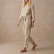 Beige linen two-piece set by FJØRNA with boat neck blouse and drawstring pants, casual and relaxed fit.