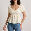 Beige summer blouse for women with sweetheart neckline and puff sleeves, by FJØRNA, shown on a model.