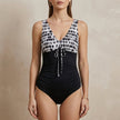 Black FJØRNA summer one-piece swimsuit for women with V-neck and bodycon fit featuring a stylish print.
