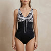 Black FJØRNA summer one-piece swimsuit for women with V-neck and bodycon fit featuring a stylish print.