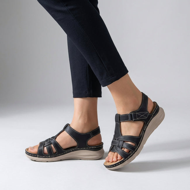 Black FJØRNA orthopedic open toe wedge sandals with cross-strap stitching and cushioned footbed.