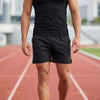 Black men's athletic shorts by FJØRNA with elastic waist and side slits, designed for comfort and active wear.