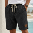 Black men's casual drawstring shorts with pockets and elegant accents, made by FJØRNA, shown on a model.