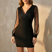 Black FJØRNA elegant mini dress for women with V-neck wrap design, shown on a model with long sleeves and a fitted silhouette.