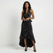 Black satin halter neck maxi dress with bow tie waist and ruffled hem, by FJØRNA, featuring elegant draping and flowing fabric.