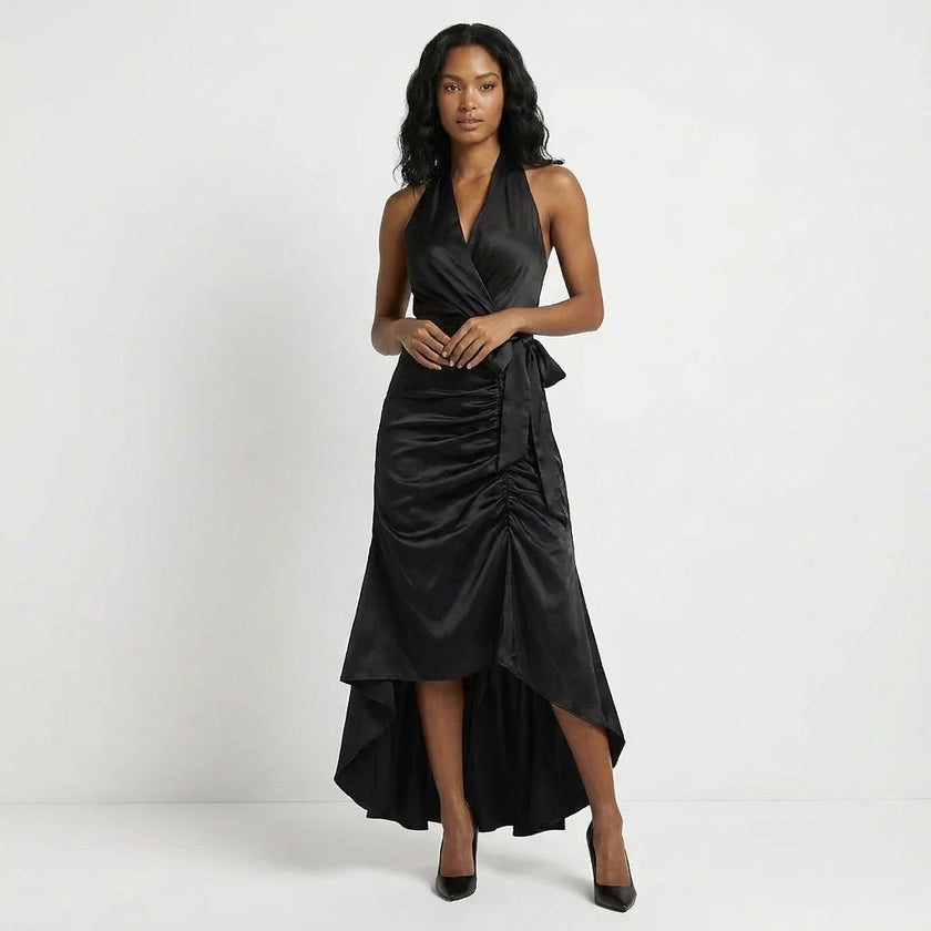 Black satin halter neck maxi dress with bow tie waist and ruffled hem, by FJØRNA, featuring elegant draping and flowing fabric.