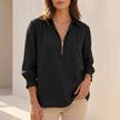 Black linen summer blouse for women with V-neck and long sleeves from FJØRNA, displayed on a hanger against a neutral background.