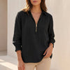 Black linen summer blouse for women with V-neck and long sleeves from FJØRNA, displayed on a hanger against a neutral background.