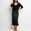 FJØRNA black relaxed V-neck knit top and satin maxi skirt set, showcasing the stylish two-piece ensemble with a comfortable fit.