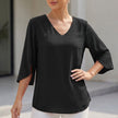 Black FJØRNA women's V-neck blouse with curved hem and slit sleeves, flowing design perfect for casual or dressy occasions.