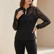 Black FJØRNA fitted sheer lace blouse with ruffled tie-neck and floral detailing, styled as a women's tops fashion piece.