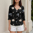 Black floral V-neck summer blouse for women with denim buttons, from FJØRNA, featuring short sleeves and a relaxed fit.