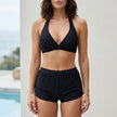 Black FJØRNA women's summer bikini with halter neck and ruched design, featuring a fitted swimwear style for beachwear or poolside.