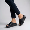 Black FJØRNA orthopedic platform slide sandals with slip-on open-toe design and cushioned footbed.