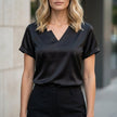 Black FJØRNA summer blouse for women with V-neck, short satin sleeves, casual style, versatile women's top.