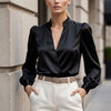 Black FJØRNA summer blouse for women with a V-neck satin design, featuring a stylish and comfortable top for warm weather.