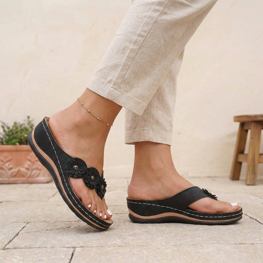 Black FJØRNA orthopedic floral applique wedge thong sandals for women with decorative flower details on the straps.