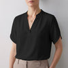 Black FJØRNA women's summer blouse with V-neck, short sleeves, and flowy fabric, perfect for warm-weather styling.