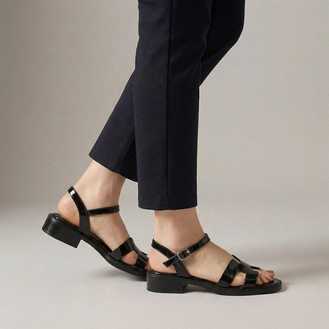 Black FJØRNA ankle-length flat sandals with ankle strap and buckle, featuring a sleek design and comfortable fit.