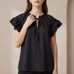 Black FJØRNA summer blouse for women with cap sleeves and ruffle details, perfect for warm weather and stylish casual wear.