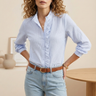 Blue FJØRNA seersucker women's blouse with ruffle trim, textured summer top, lightweight and stylish for warm weather.