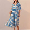 Blue FJØRNA flowing V-neck midi dress with puff sleeves and tiered skirt, displayed on a hanger.