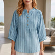 Blue striped linen summer blouse for women by FJØRNA featuring button front and relaxed fit, shown on a model.