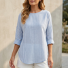 Blue FJØRNA relaxed-fit women's blouse with rolled sleeves and curved hem, shown on a model.