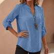 Blue women's relaxed V-neck blouse by FJØRNA with band collar and patch pocket, shown on a model.