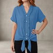 Blue FJØRNA summer blouse for women with V-neck and ruffle details, casual denim top perfect for warm weather.