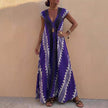 Blue FJØRNA bohemian-inspired flowing maxi dress with deep V-neck and geometric motifs, styled as an A-line silhouette.